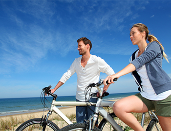 Paar auf Fahrrädern am Strand mit dem Meer im Hintergrund